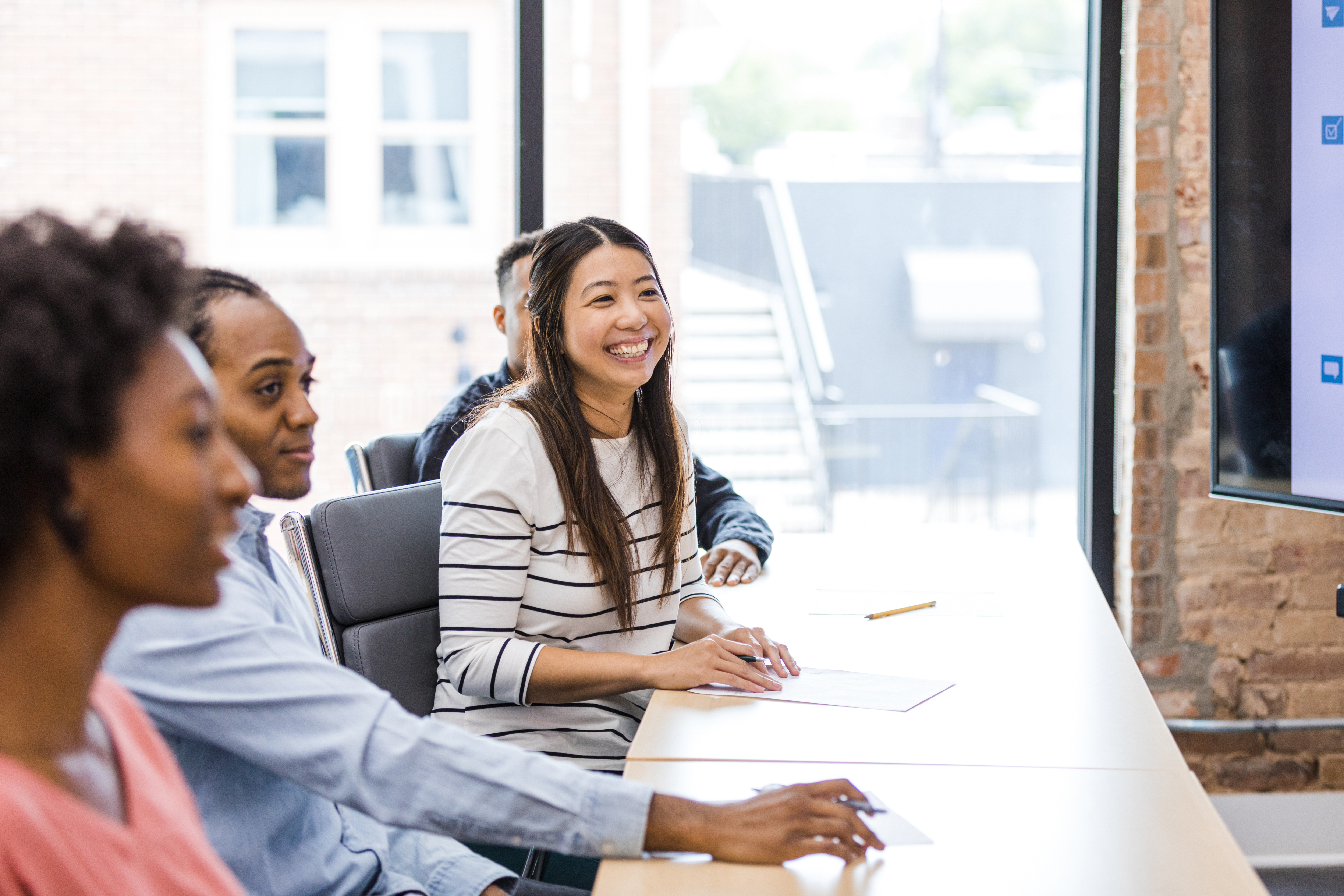 woman working at desk with colleagues in a meeting