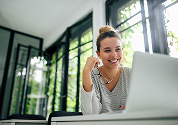 Image-woman-holding-eyeglasses-smiling-working-on-laptop