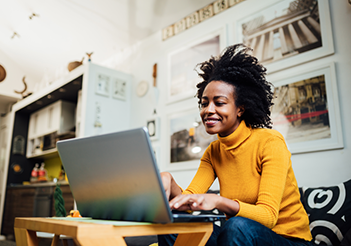 woman sitting on couch working on laptop