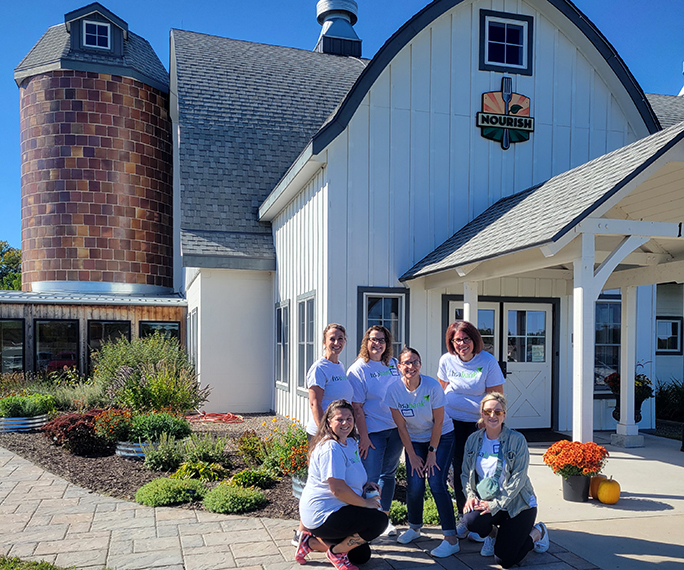 HSA Bank volunteers posing in front of a barn at Nourish Farms